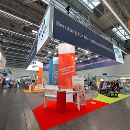 LWL-Stand auf der Rehacare 2024. Bunter Messestand mit roter Säule im Vordergrund.