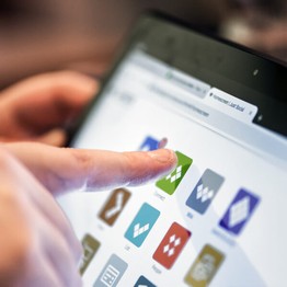 Eine Person klickt mit dem Finger auf eine App auf einem Tablet.