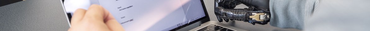 Eine Person mit Handprothese sitzt vor einem Laptop.