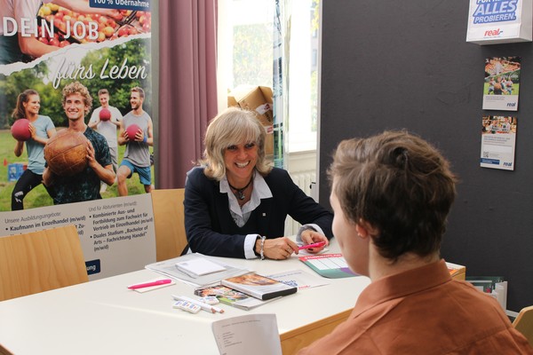 Beim ersten Job-Speed-Dating knüpften Arbeitgeber und Schüler mit Handicap erste Kontakte. Melanie Tegas beschreibt Justin die beruflichen Möglichkeiten in ihrem Betrieb.