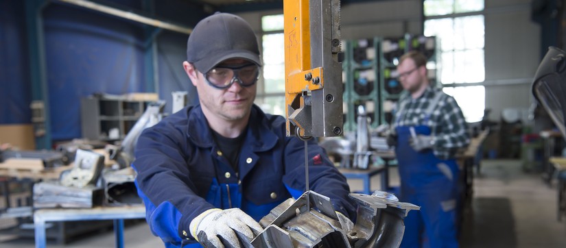 Ein Mann zersägt mit einer Maschine ein Stück Metall