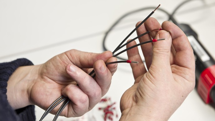 Zwei Hände halten Kabel in der Hand.